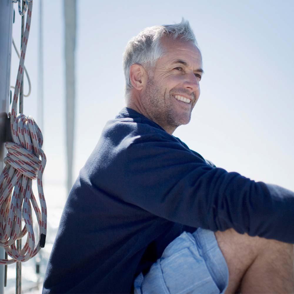 Mann sitzt auf einem Boot und lächelt